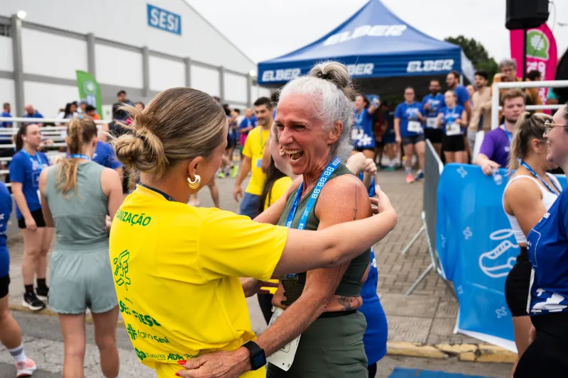 Corredora recebe abraço de integrante da organização após concluir a prova